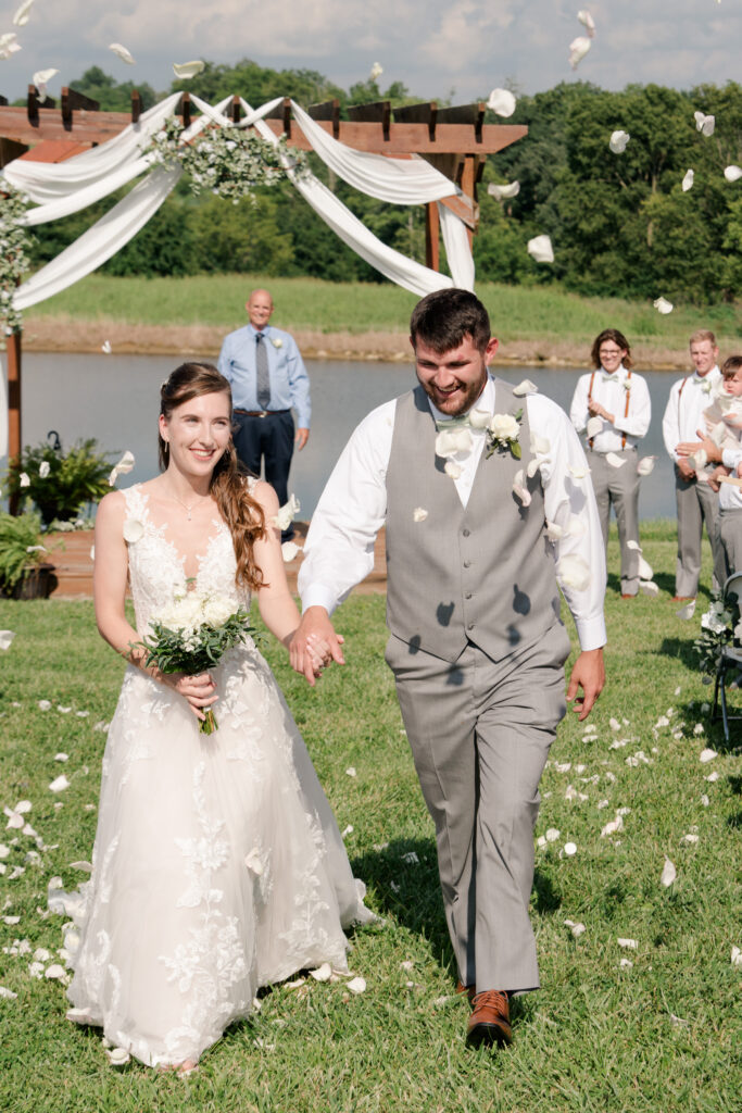 summer wedding bride and groom recess from ceremony with rose petals