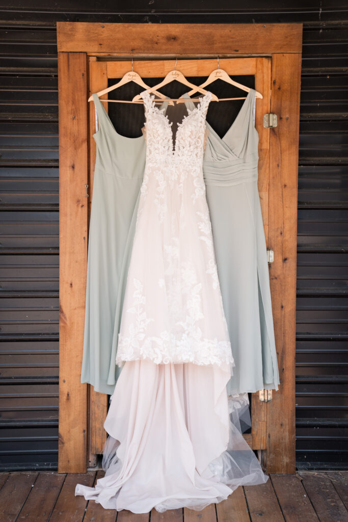 bridal gown and bridesmaids dresses hanging in barn