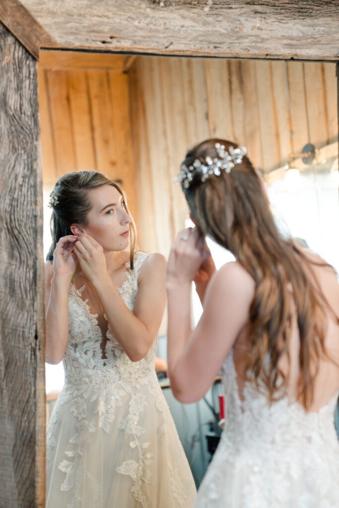 bride putting in earrings on wedding day 